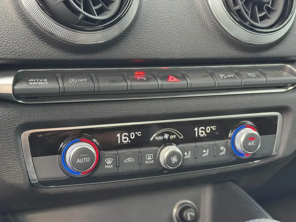 Gros plan sur la console centrale de l'Audi A3 Cabriolet gris, montrant les commandes de climatisation bi-zone et boutons de fonction.