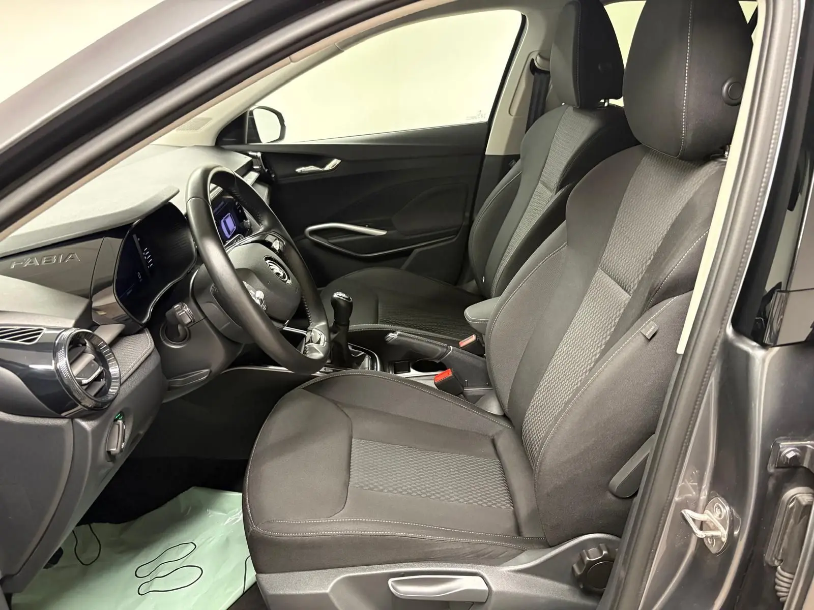 Vue intérieure côté conducteur de la Skoda Fabia 2023 gris graphite, montrant sièges, volant et tableau de bord moderne.