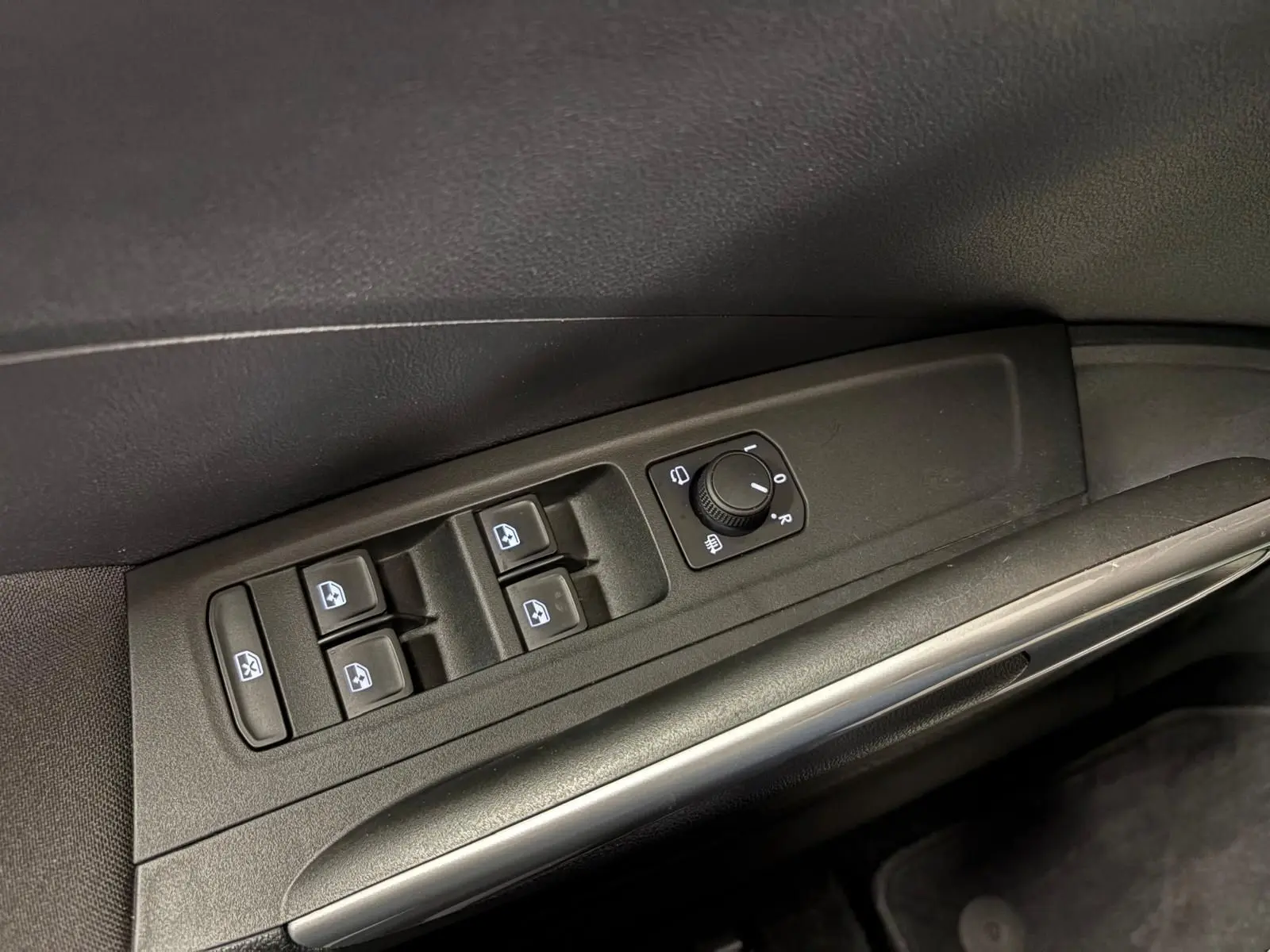 Gros plan sur la commande des vitres et rétroviseurs côté conducteur de la Skoda Fabia 2023 en intérieur noir.