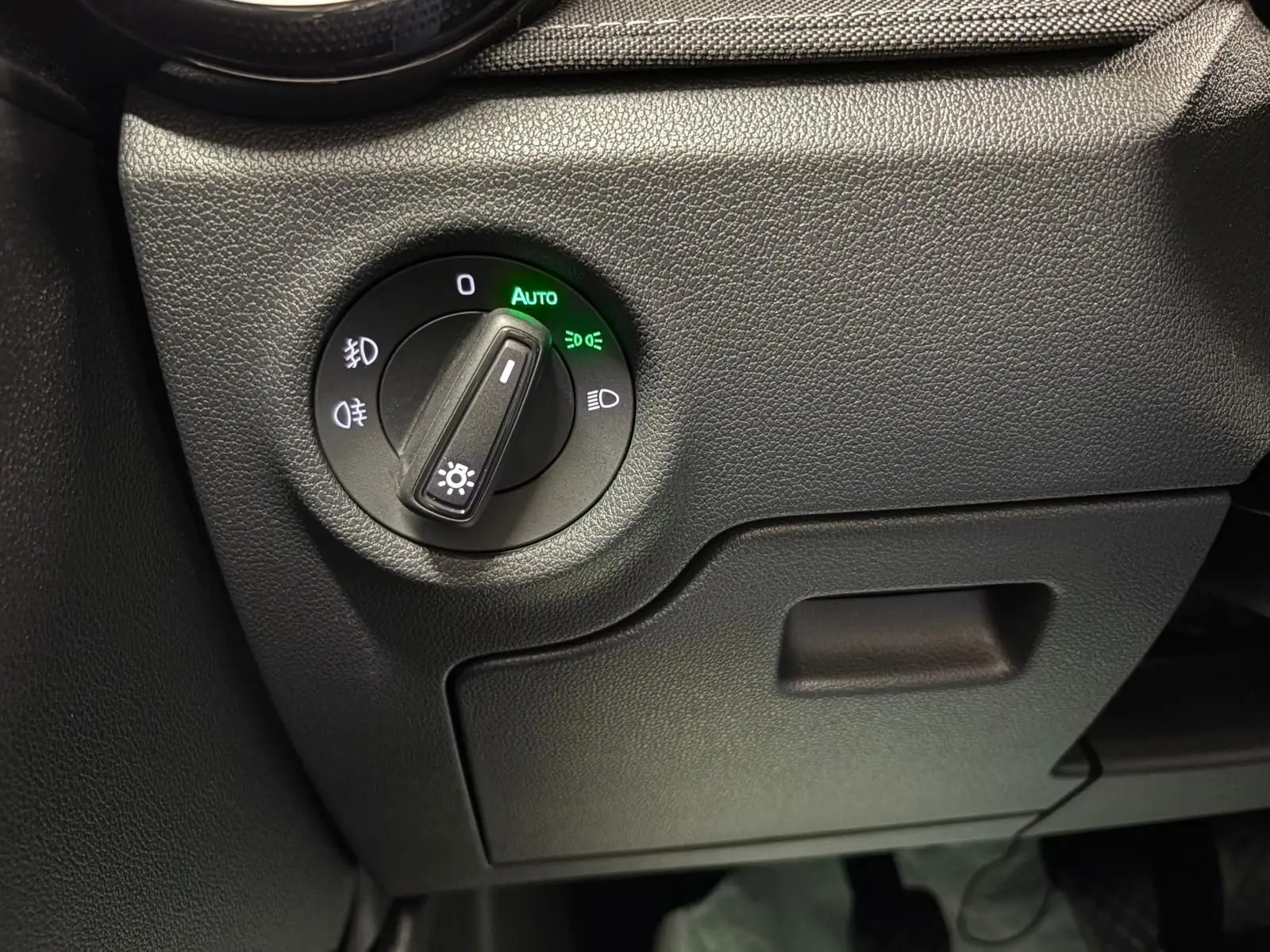 Gros plan sur le bouton de commande des phares avec mode automatique allumé dans l’habitacle de la Skoda Fabia Gris Graphite 2023.