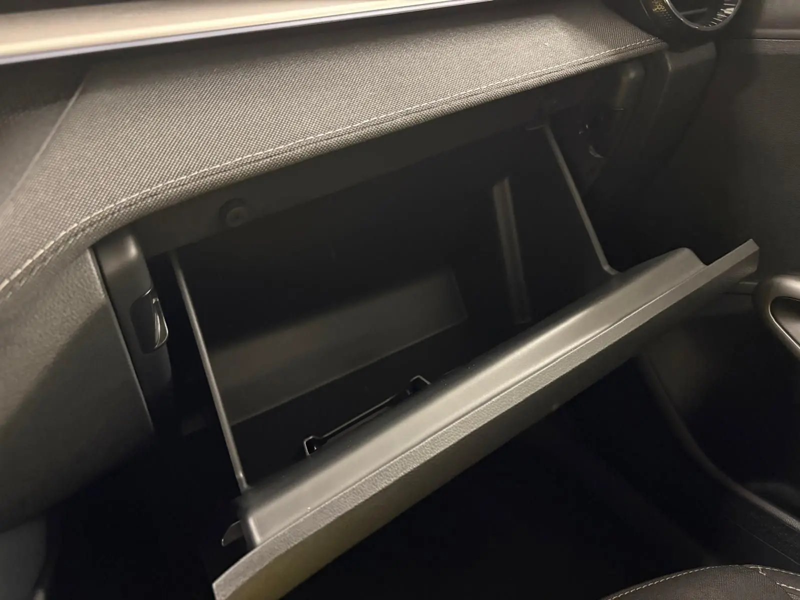 Gros plan sur la boîte à gants ouverte de la Skoda Fabia 2023, intérieur noir avec finition sobre.