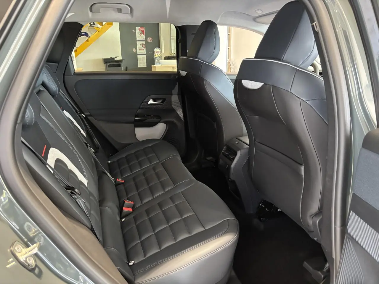 Vue intérieure côté gauche de la banquette arrière en cuir noir du Citroën C5 Aircross vert 2026, avec appuis-tête et portières visibles.