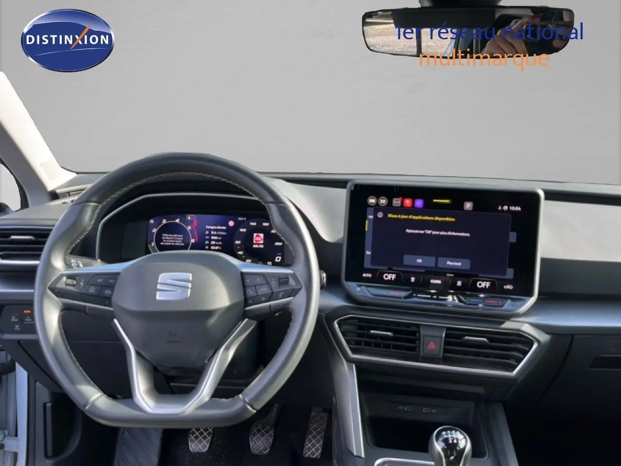 Vue intérieure frontale du tableau de bord de la SEAT LEON blanc neige 2025 avec volant multifonction et écran tactile central.