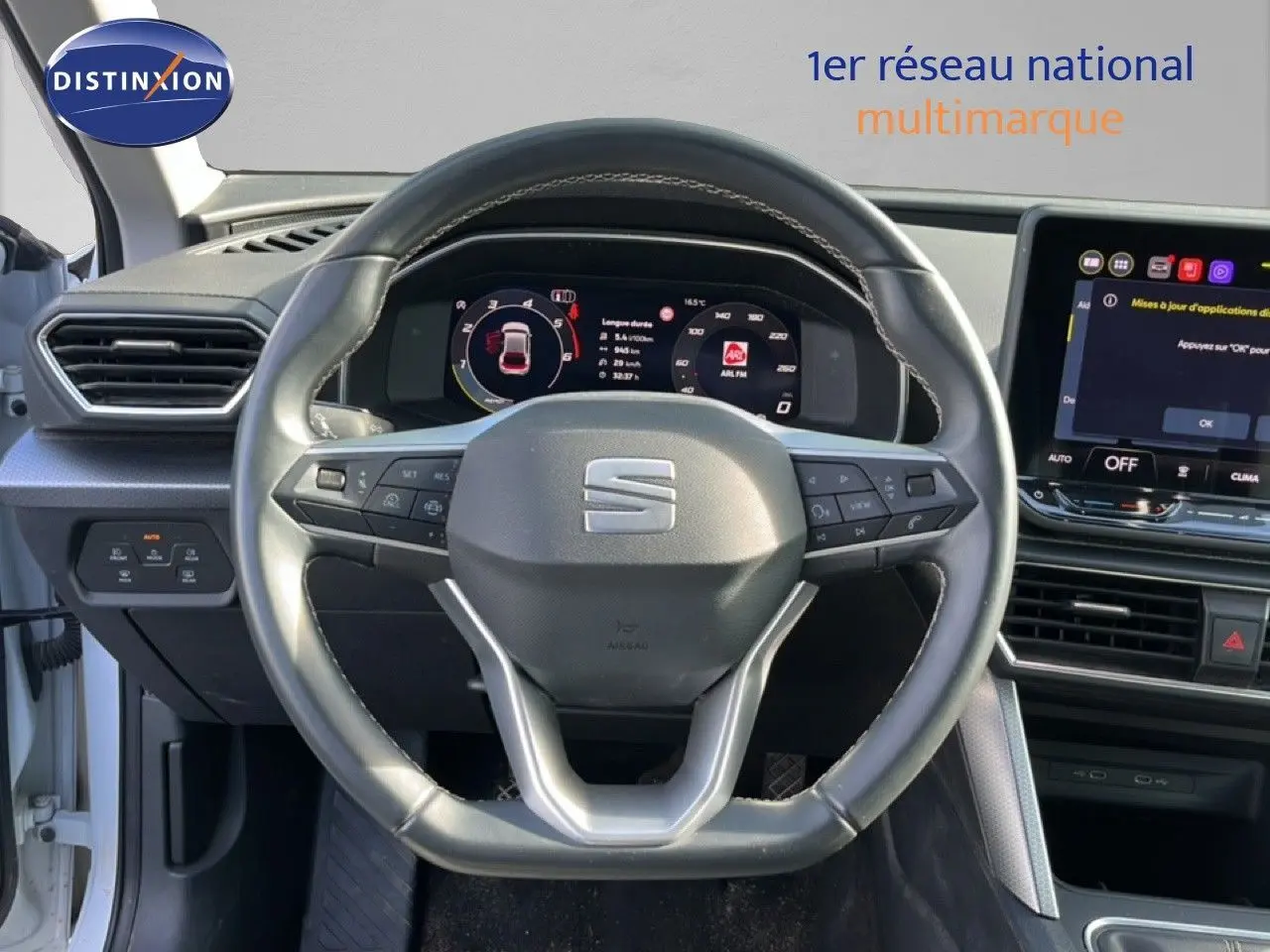 Vue rapprochée du volant et du tableau de bord numérique d’un SEAT Leon blanc neige 2025, intérieur moderne.