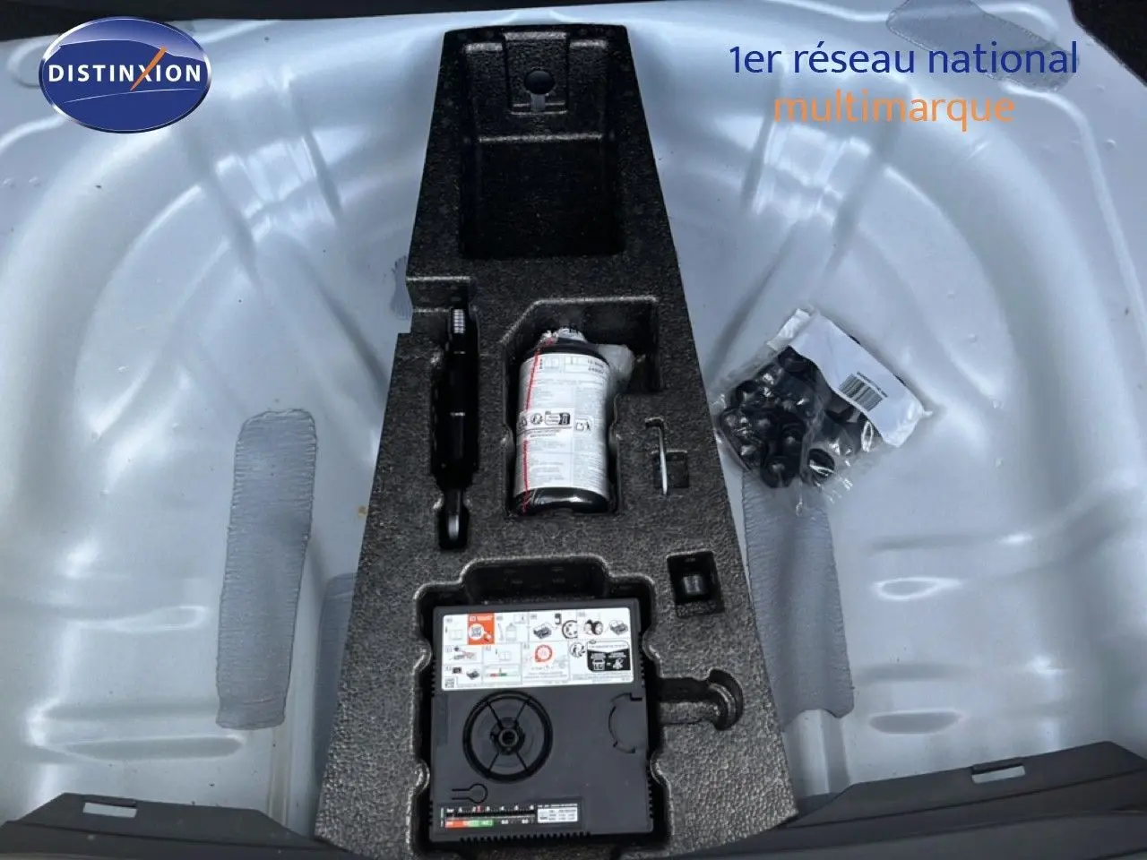 Vue plongeante sur le coffre avec kit de réparation pneu et accessoires dans un SEAT LEON blanc neige 2025.