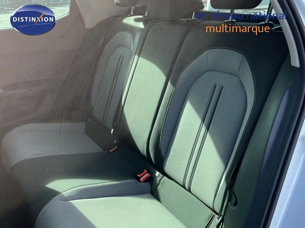 Vue intérieure des sièges arrière en tissu gris noir du SEAT LEON blanc neige, avec ceinture de sécurité visible côté droit.