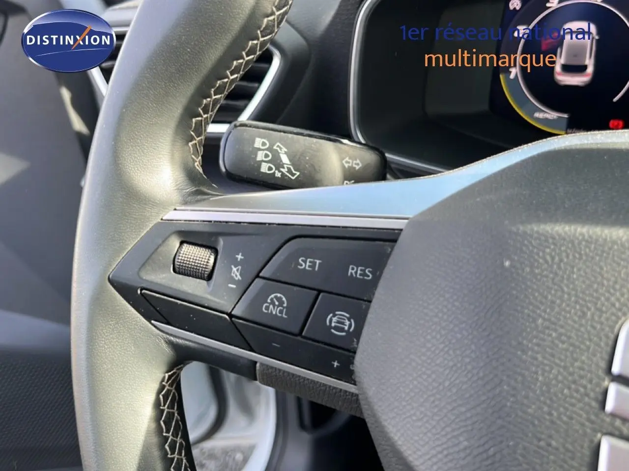 Gros plan sur le volant de la SEAT LEON blanc neige, mettant en valeur les commandes multifonctions côté gauche.
