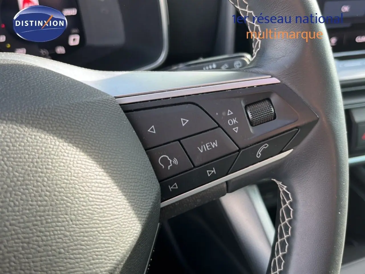 Gros plan sur les commandes multifonctions à droite du volant en cuir noir du SEAT Leon blanc neige 2025.