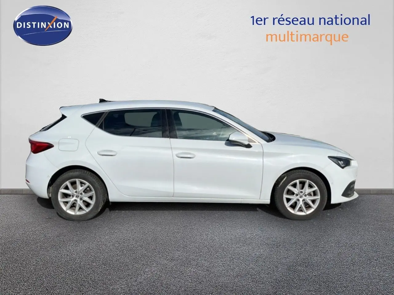 Vue de profil côté gauche d'une SEAT Leon blanc neige, compacte cinq portes avec jantes alliage et lignes épurées.