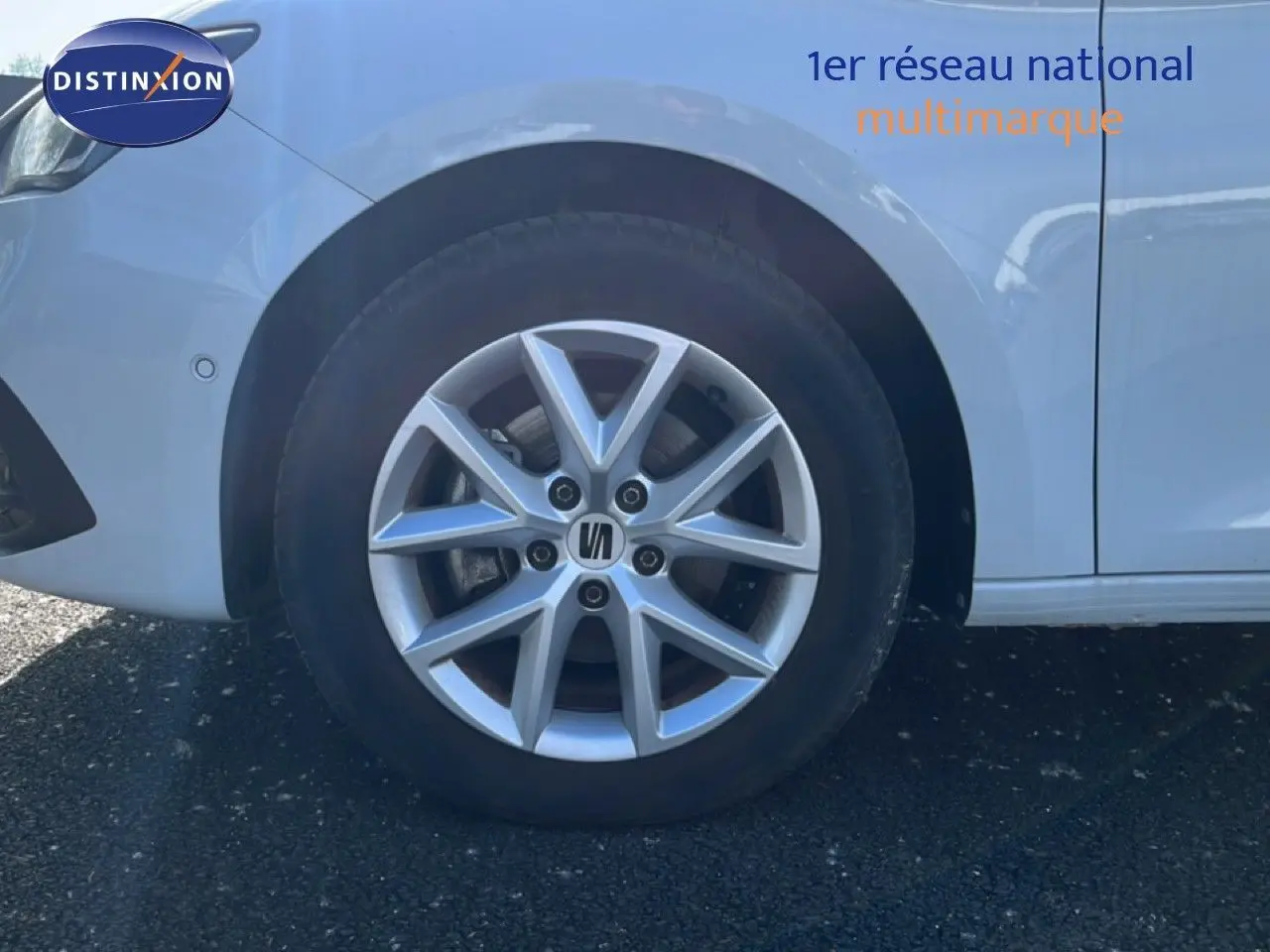 Gros plan sur la roue avant gauche d'une SEAT LEON blanc neige, mettant en valeur la jante alliage à 5 branches doubles.