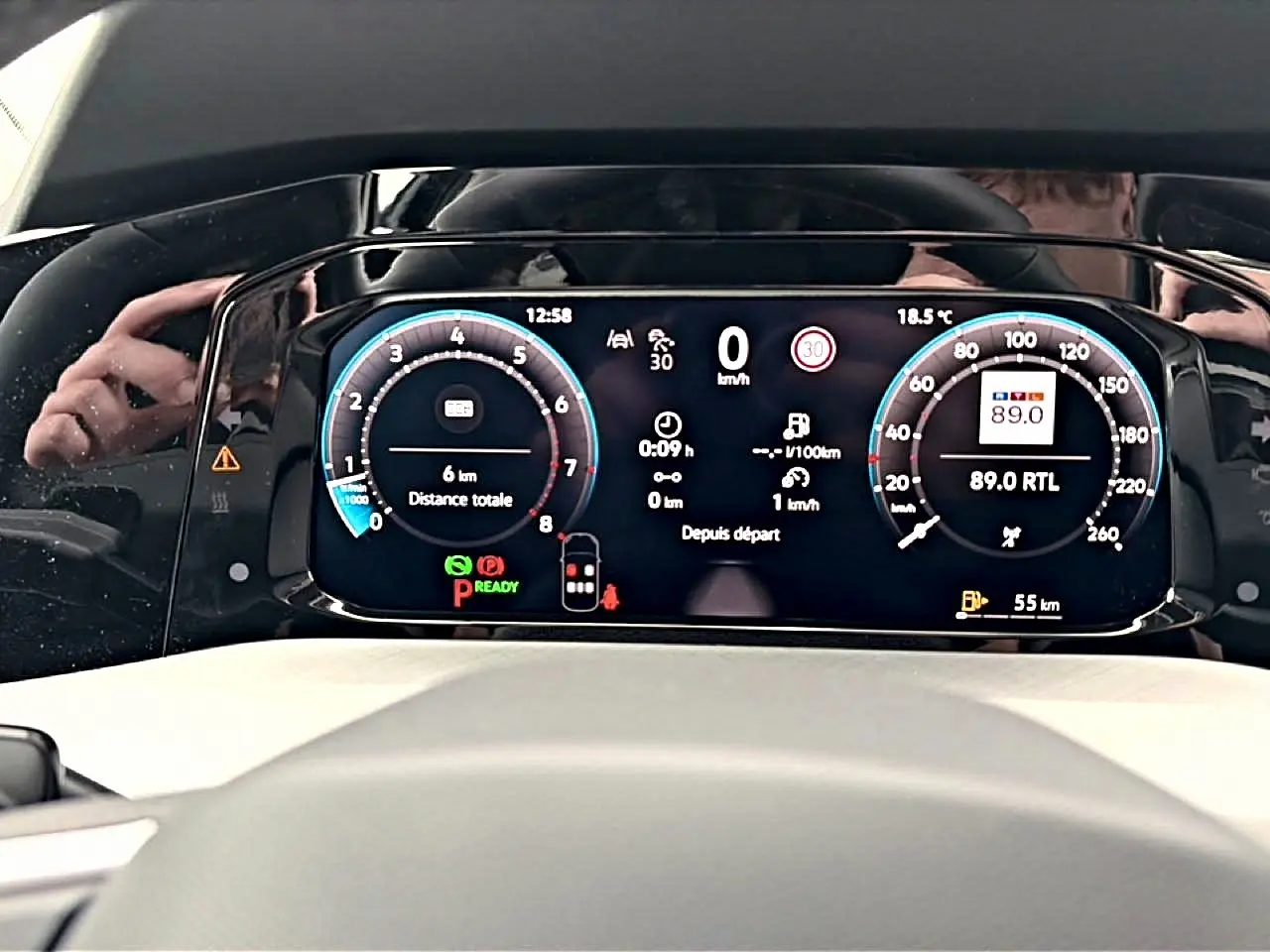 Vue rapprochée du tableau de bord numérique de la Volkswagen Golf noire, affichant la vitesse, la radio et les alertes.