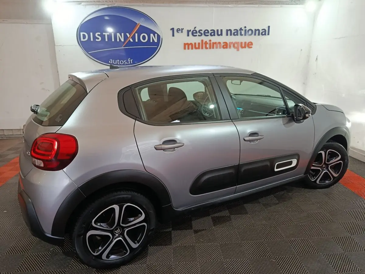 Citroën C3 gris clair vue de profil droit en intérieur, avec protections latérales noires et jantes distinctives.