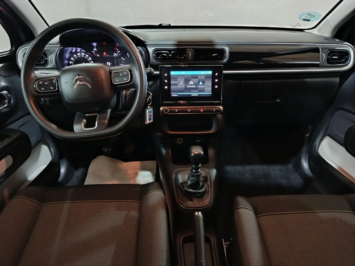 Vue intérieure avant de la Citroën C3 2024 gris clair, avec tableau de bord central tactile et volant multifonctions.