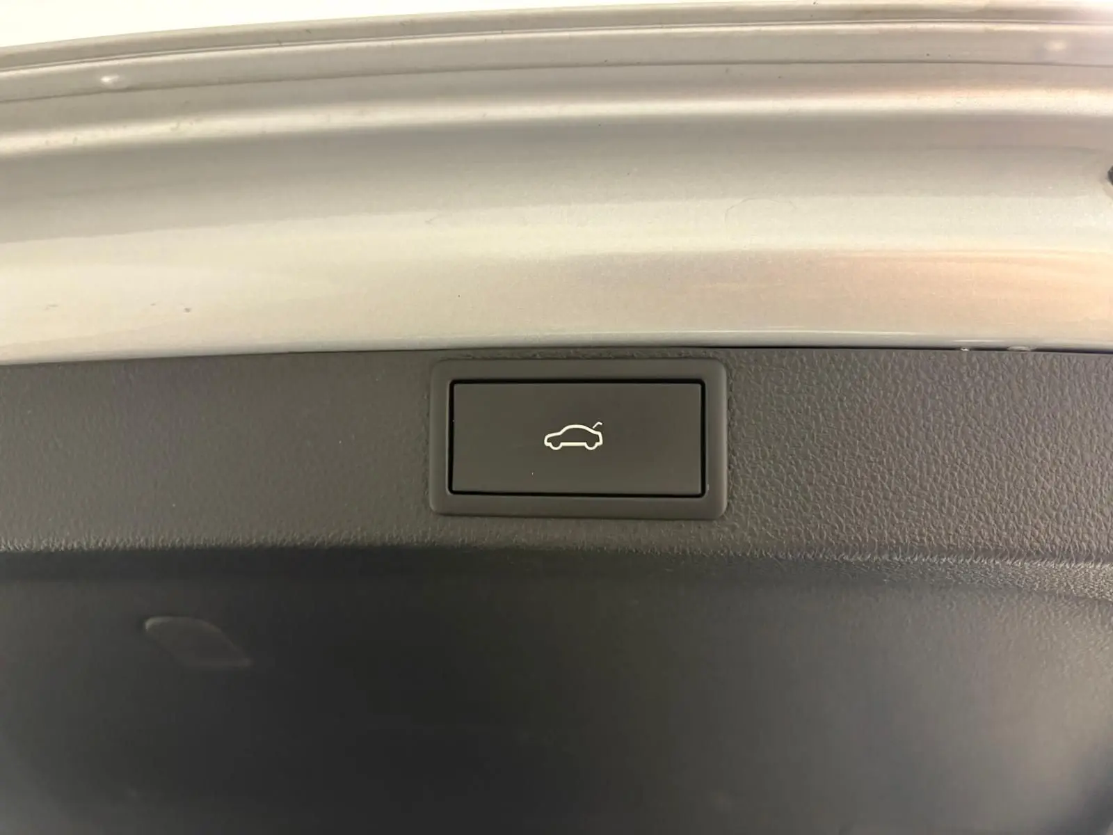 Bouton d'ouverture électrique du coffre sur la trappe intérieure d'une Skoda Octavia Combi gris argent 2023.