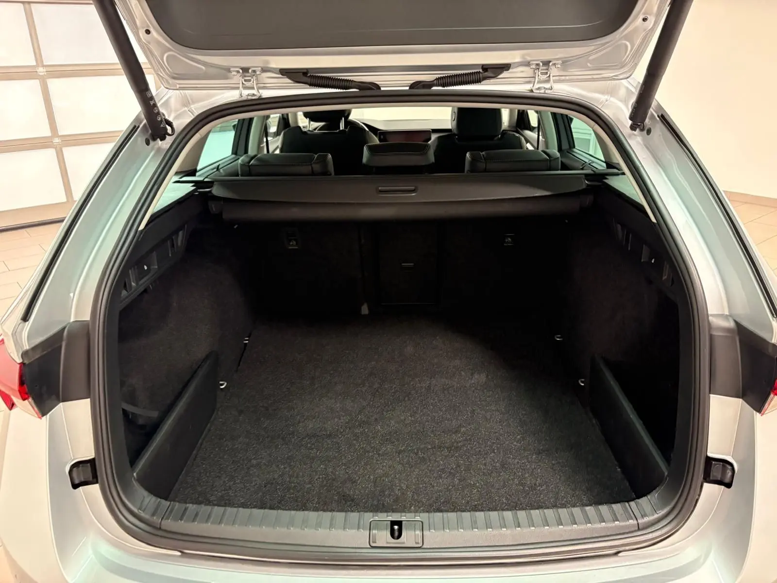 Coffre ouvert vu de l'arrière d'une Skoda Octavia Combi gris argent 2023, montrant l'espace de chargement vide.