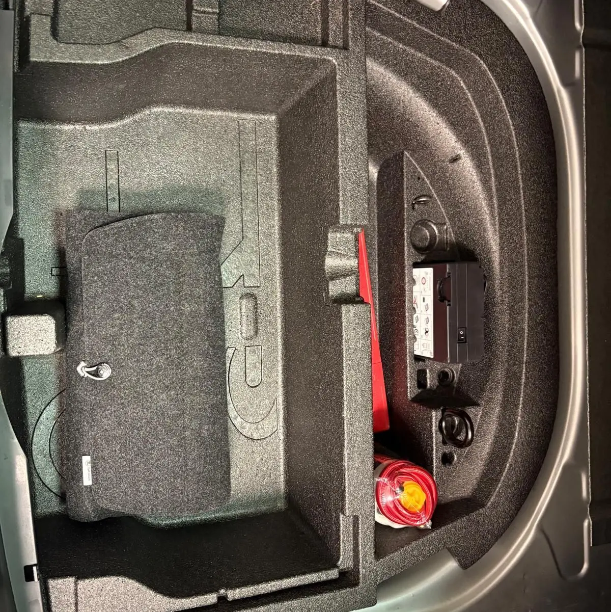 Rangement sous plancher de coffre du Skoda Octavia Combi gris argent 2023, avec kit de sécurité et espace compartimenté.