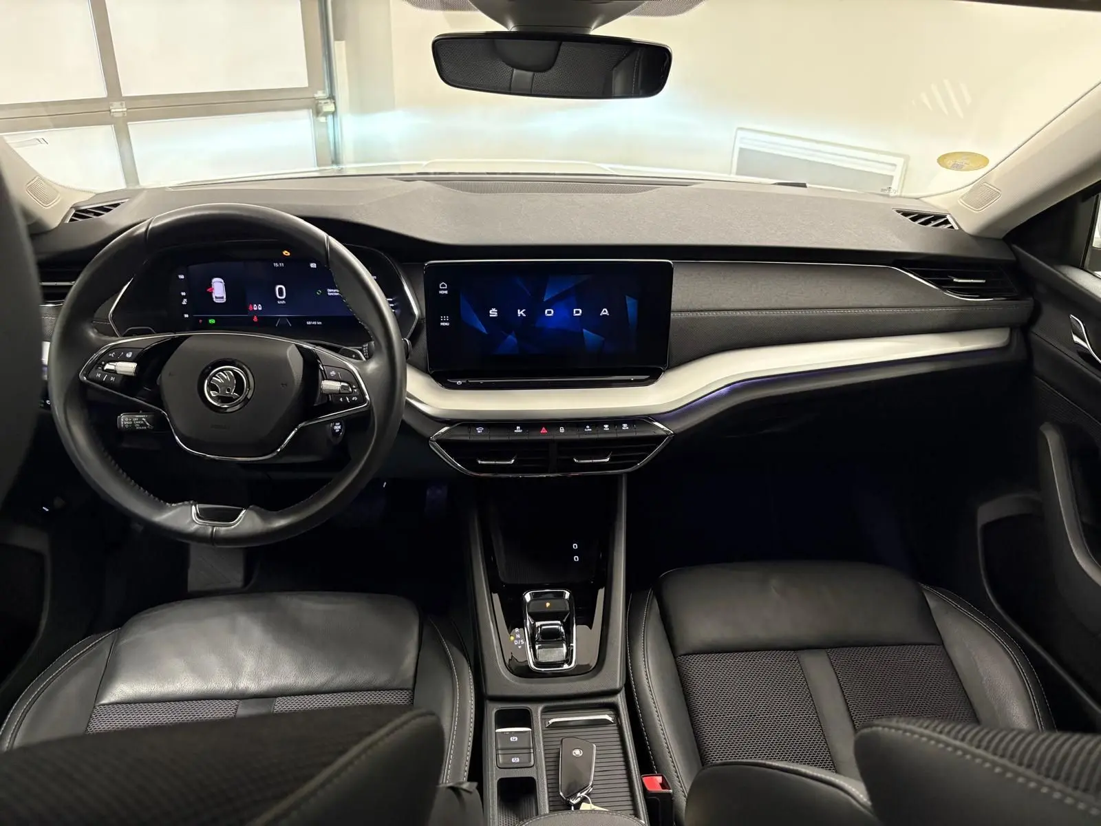 Intérieur noir de la Skoda Octavia Combi 2023, vue frontale sur le tableau de bord et volant avec écran digital.