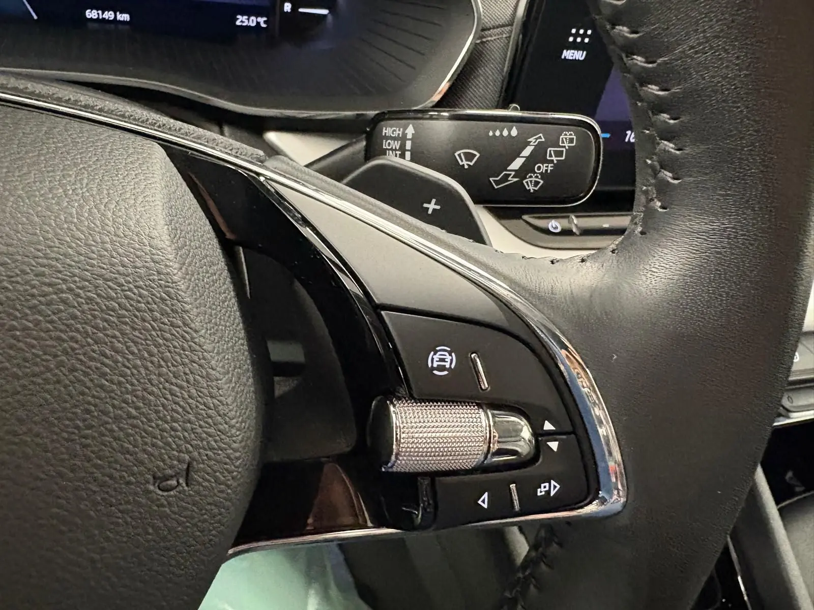 Gros plan sur la commande de régulateur de vitesse au volant cuir noir d'une Skoda Octavia Combi gris argent 2023.