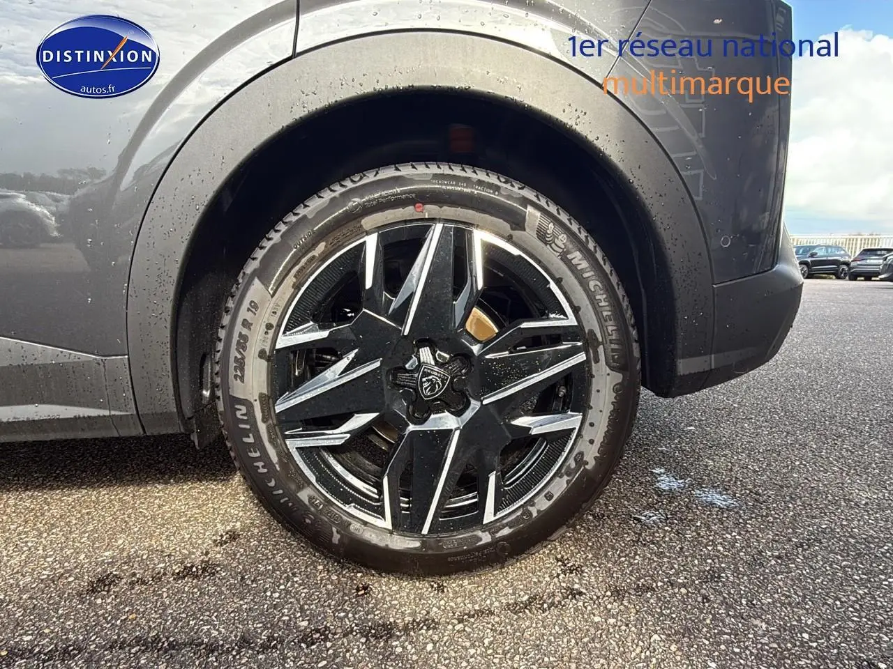 Gros plan sur la roue arrière droite du Peugeot 3008 gris titane, mettant en valeur la jante alu au design moderne.