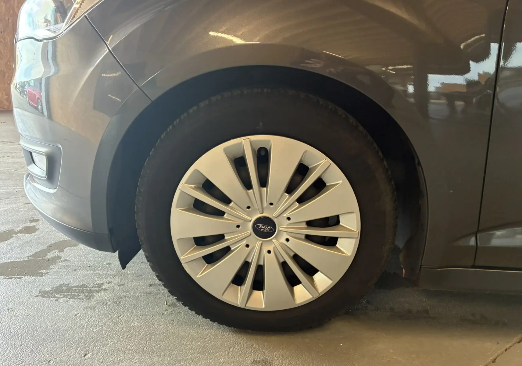 Gros plan sur la roue avant gauche d'une Ford C-MAX gris métallisé avec enjoliveur à rayons fins.