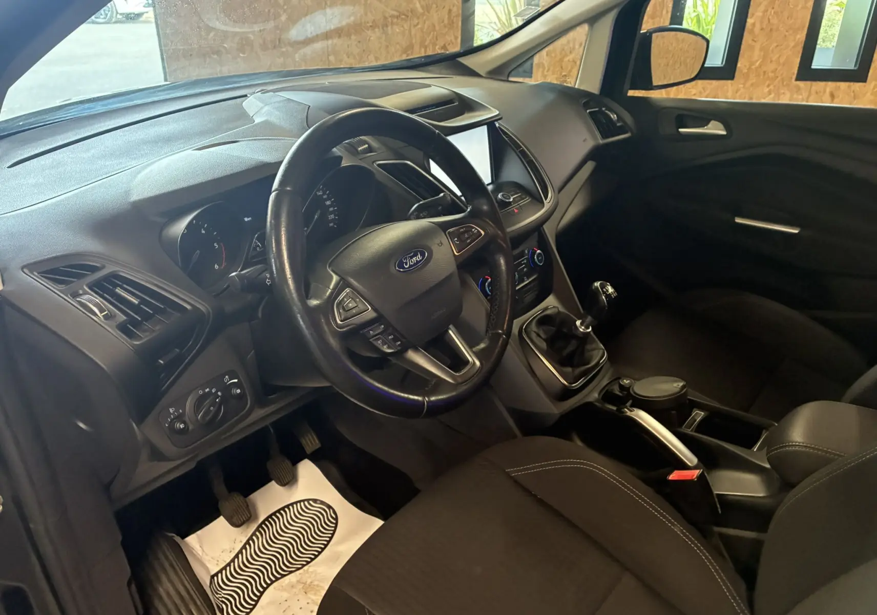 Intérieur avant droit du Ford C-MAX gris 2015, volant multifonction, boîte manuelle et tableau de bord moderne.