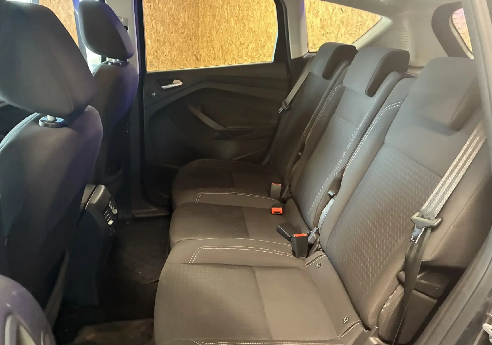 Vue latérale droite de l'habitacle arrière du Ford C-MAX 2015, sièges tissu gris avec ceintures de sécurité visibles.