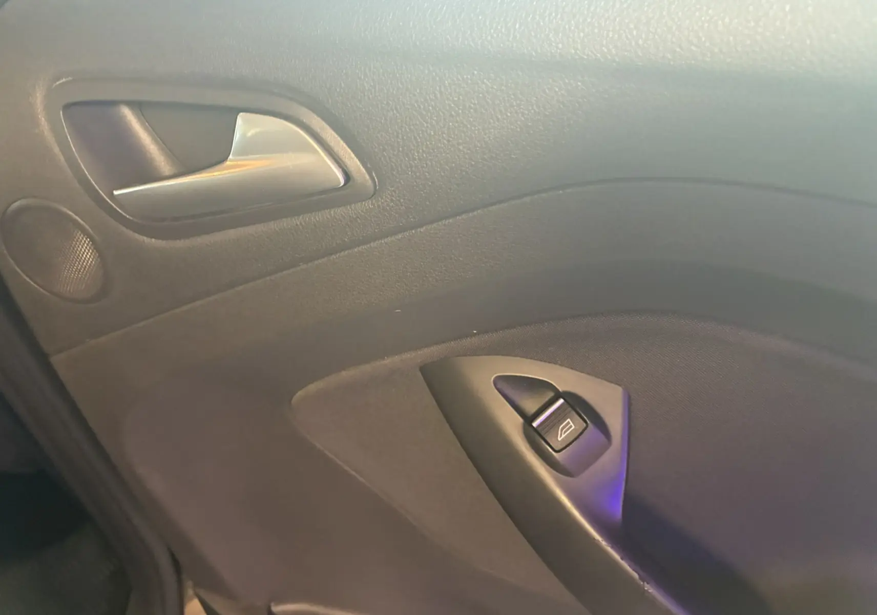 Gros plan sur la poignée intérieure et le bouton de lève-vitre côté gauche d'une Ford C-MAX gris 2015.