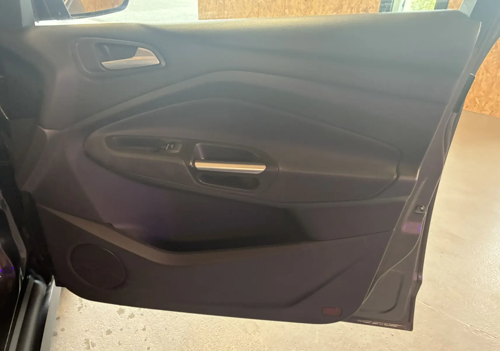 Gros plan sur la porte avant gauche intérieure gris foncé du Ford C-MAX 2015, avec poignée et commande de vitre.