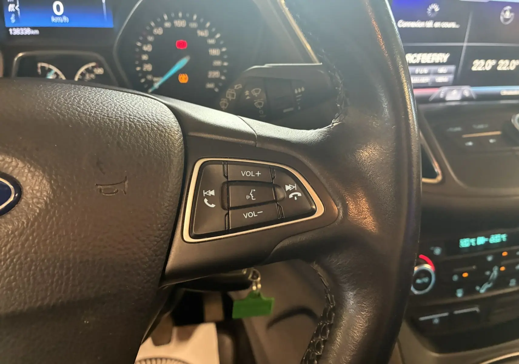 Gros plan sur le volant en cuir noir du Ford C-MAX gris, montrant les commandes audio et téléphone intégrées.