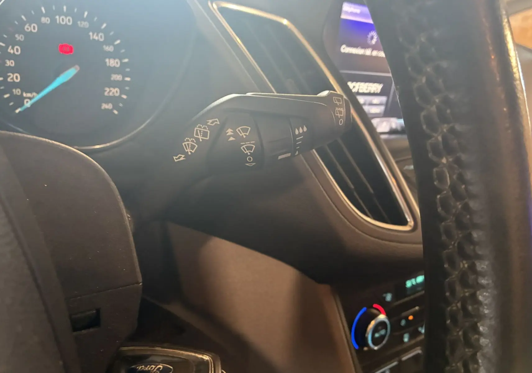 Gros plan sur la manette d'essuie-glace à gauche du volant dans l'habitacle gris noir du Ford C-MAX 2015.