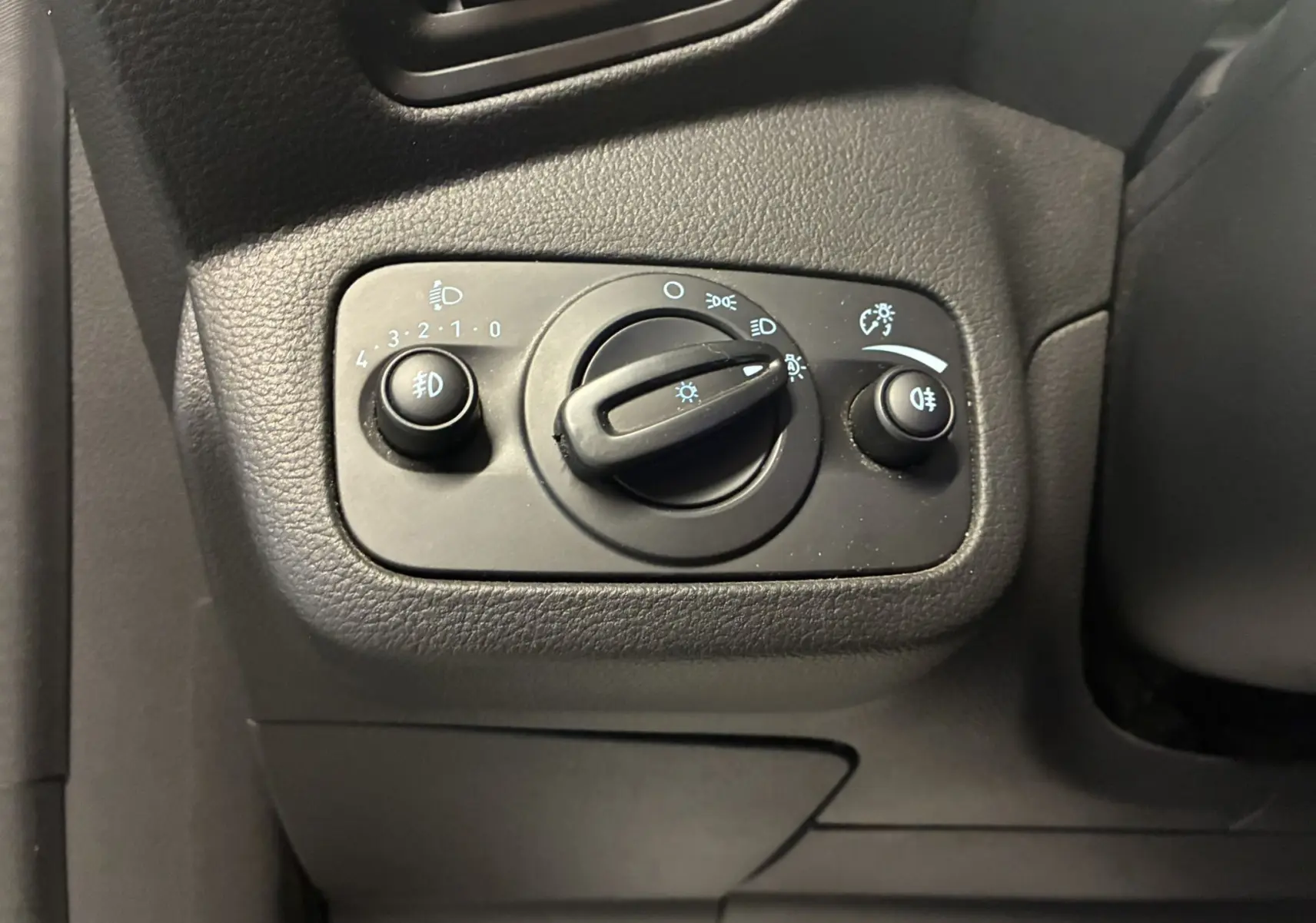 Gros plan sur le panneau de commande des phares d’un Ford C-MAX gris de 2015, avec boutons de réglage et interrupteur rotatif.
