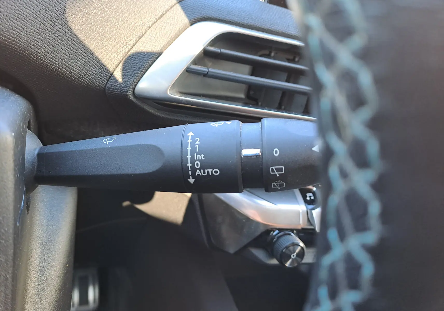 Gros plan sur la commande d’essuie-glace à gauche du volant dans l’habitacle gris d’un Peugeot 5008 2019.