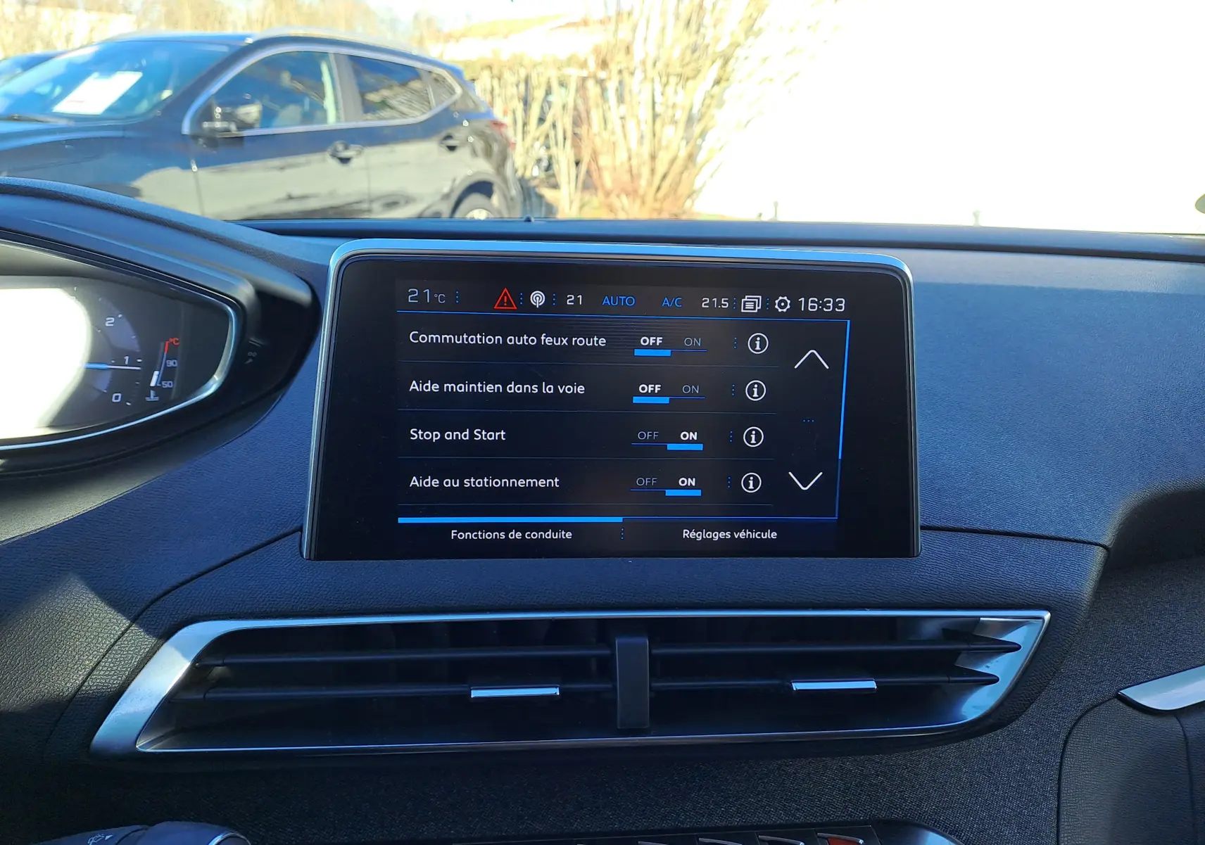Vue intérieure du tableau de bord du Peugeot 5008 gris, avec écran tactile affichant les réglages d'aides à la conduite.