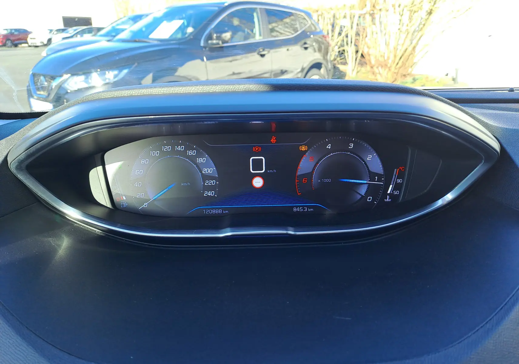 Vue rapprochée du tableau de bord numérique du Peugeot 5008 gris, affichant vitesse, compte-tours et température moteur.