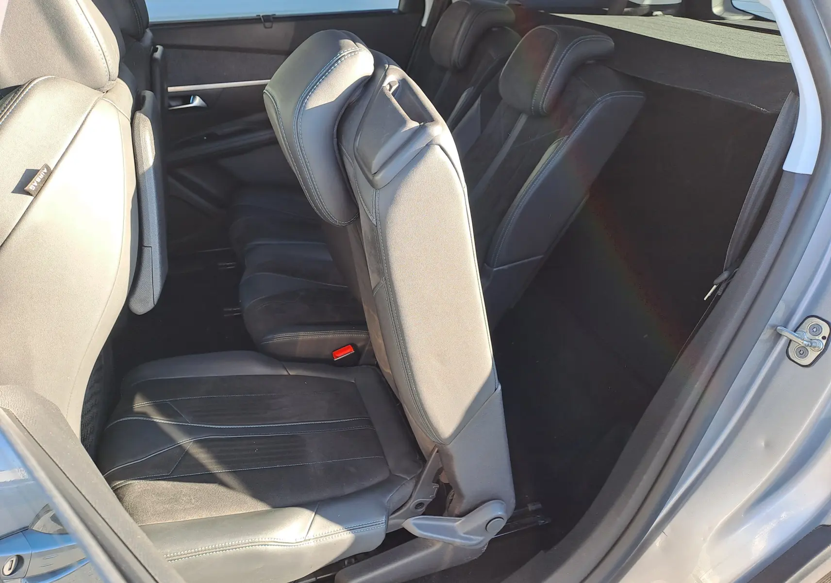 Vue intérieure côté droit du Peugeot 5008 gris 2019, montrant les sièges arrière en cuir et alcantara avec accès à la troisième rangée.