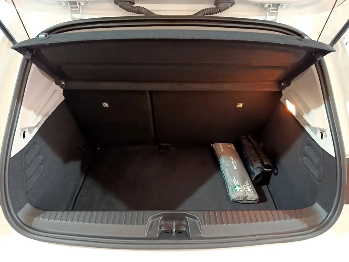 Coffre ouvert de la Renault Clio Business blanc, vue arrière, avec kit de secours et éclairage intérieur allumé.