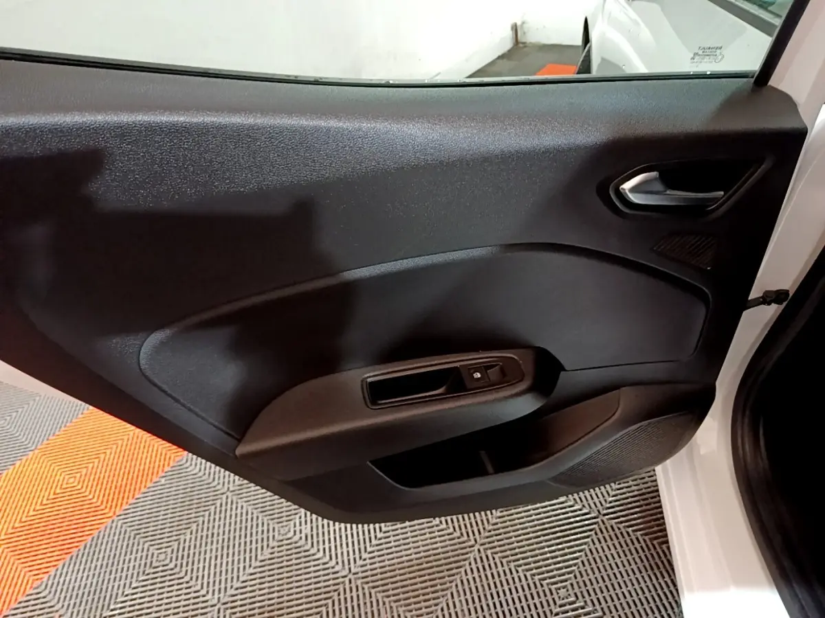 Vue intérieure de la porte avant droite noire d'une Renault Clio blanche 2023, avec poignée et commande de vitre électrique.