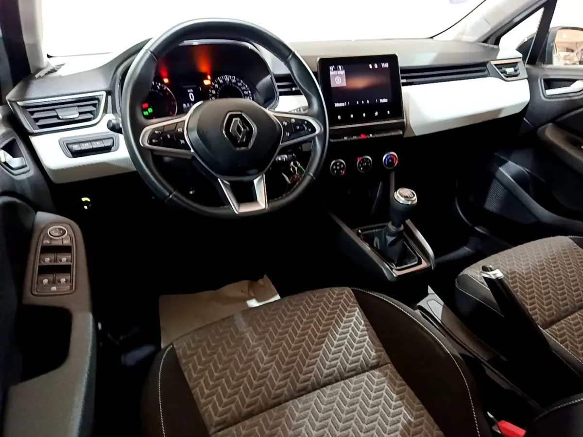 Vue intérieure avant de la Renault Clio Business 2023, tableau de bord blanc, volant cuir noir, écran tactile central.