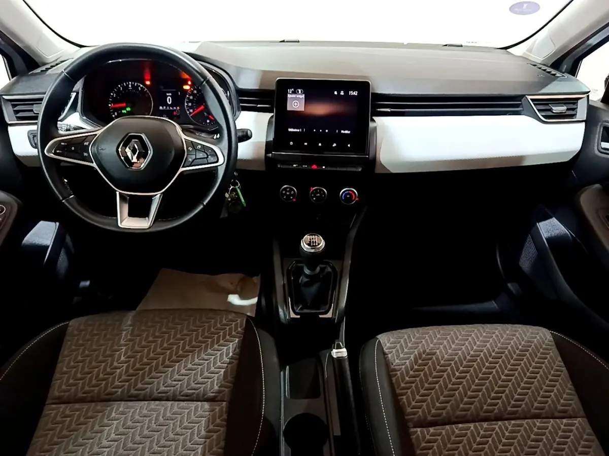 Vue intérieure avant de la Renault Clio Business 2023, tableau de bord noir et blanc avec écran tactile central et volant multifonctions.