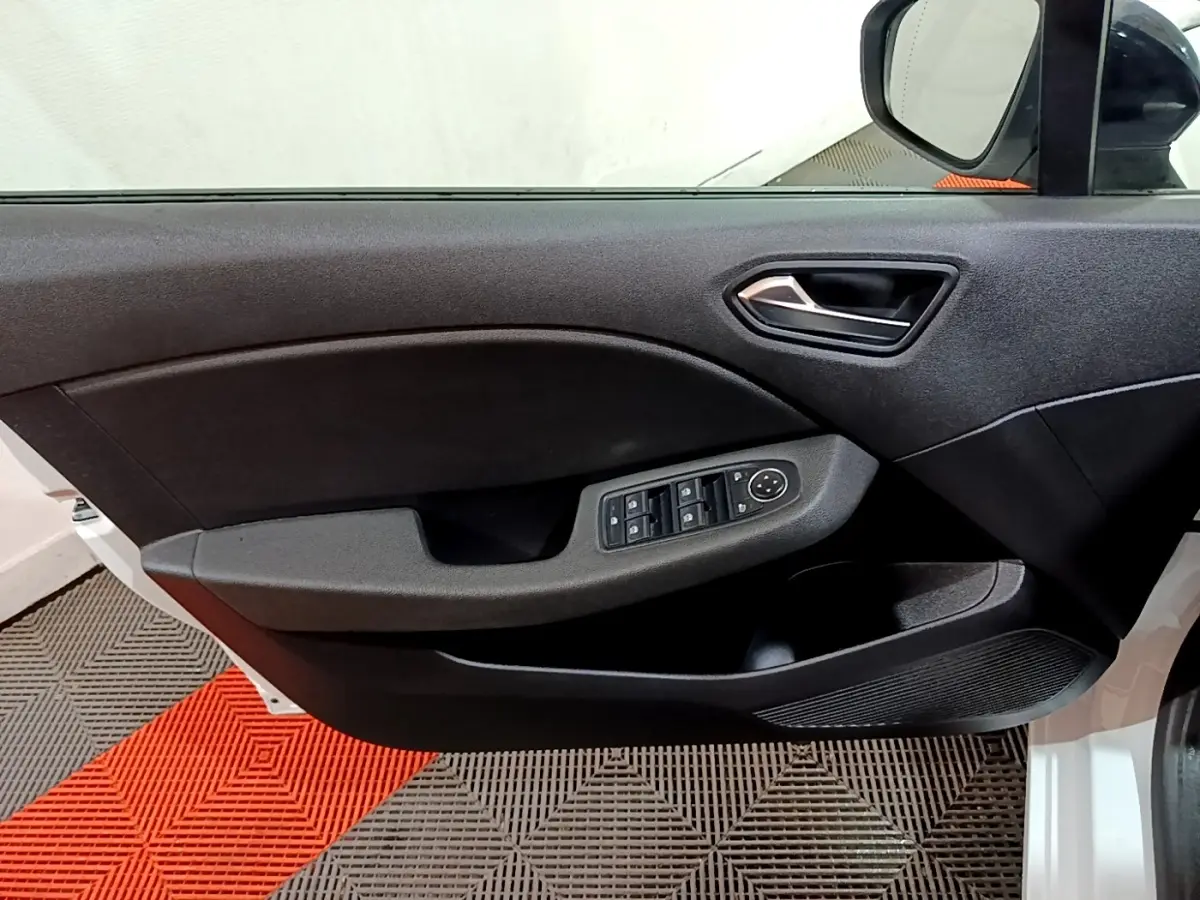 Vue intérieure sur la porte avant gauche noire de la Renault Clio blanche, avec commandes des vitres et rétroviseur visible.