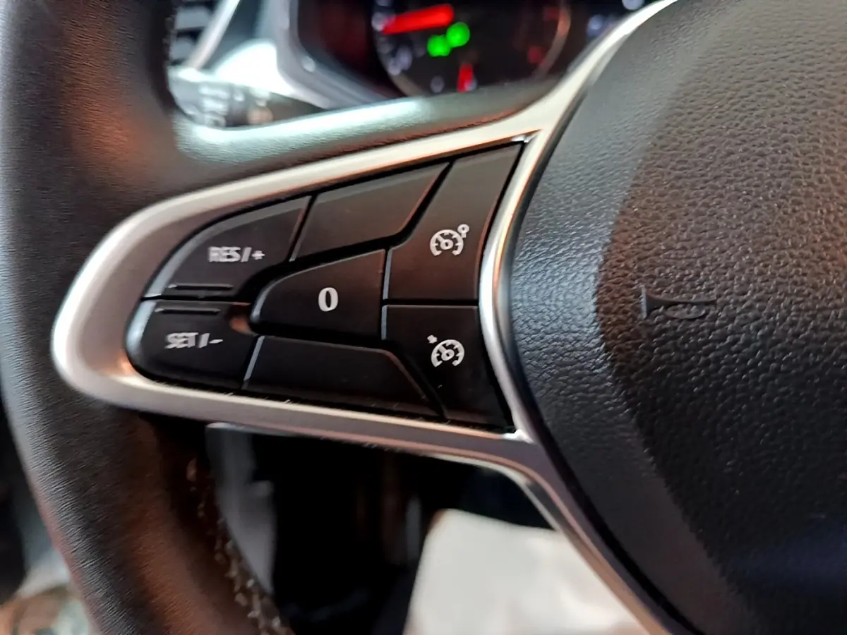 Gros plan sur les commandes de régulateur de vitesse au volant cuir noir de la Renault Clio Business blanc.