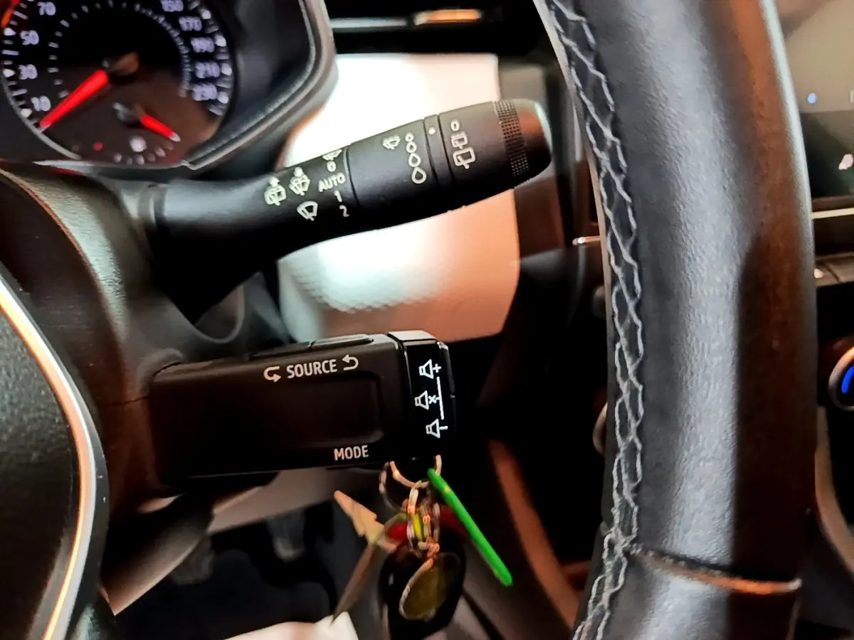 Gros plan intérieur sur la commande au volant et le commodo d’essuie-glace d’une Renault Clio Business blanche de 2023.