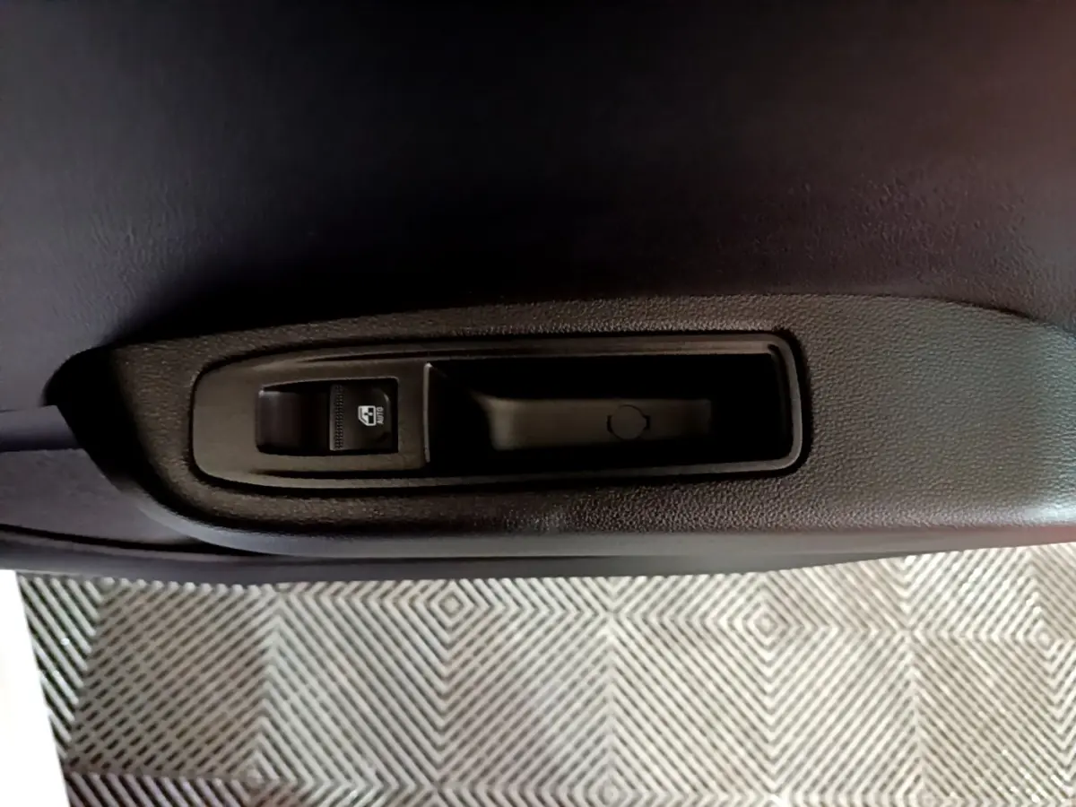 Gros plan sur la commande de lève-vitre côté intérieur d'une porte de Renault Clio Business blanc, 2023.