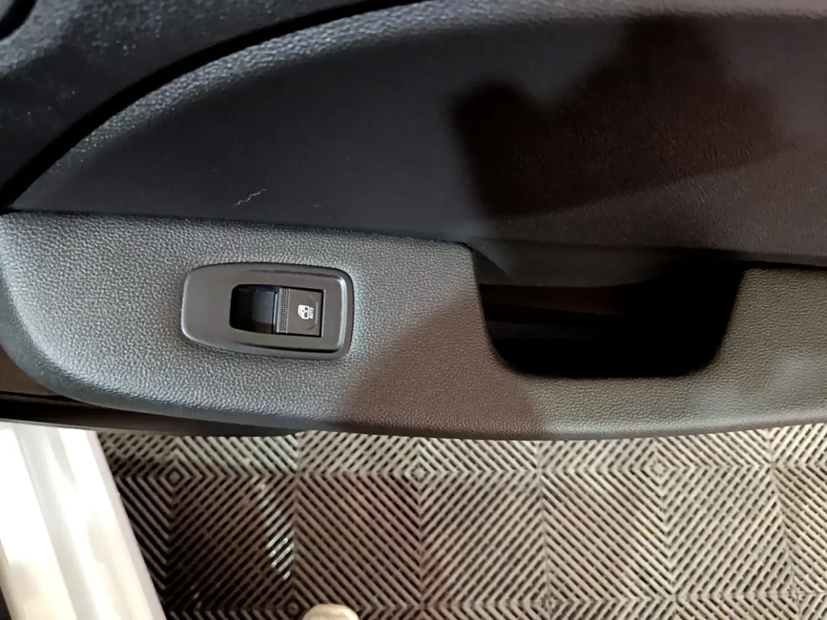 Détail de la commande de verrouillage des portes sur la portière intérieure côté conducteur d’une Renault Clio blanche.