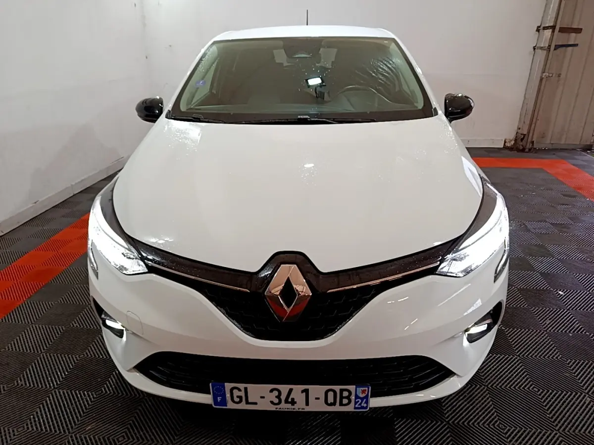 Vue avant d'une Renault Clio Business blanche avec phares LED allumés dans un garage.