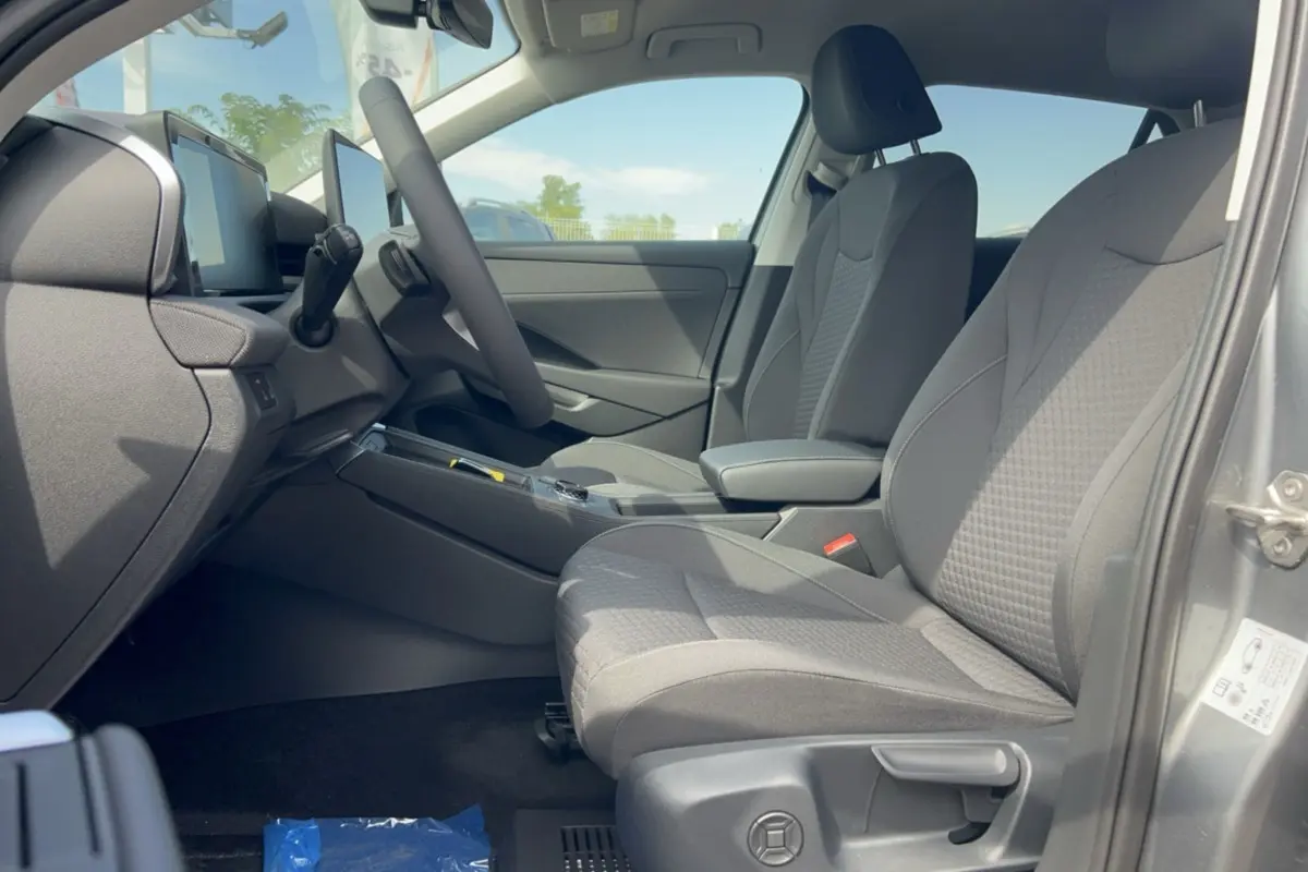 Vue intérieure côté conducteur du Volkswagen T-Roc gris loup 2026, sièges tissu et accoudoir central visibles.
