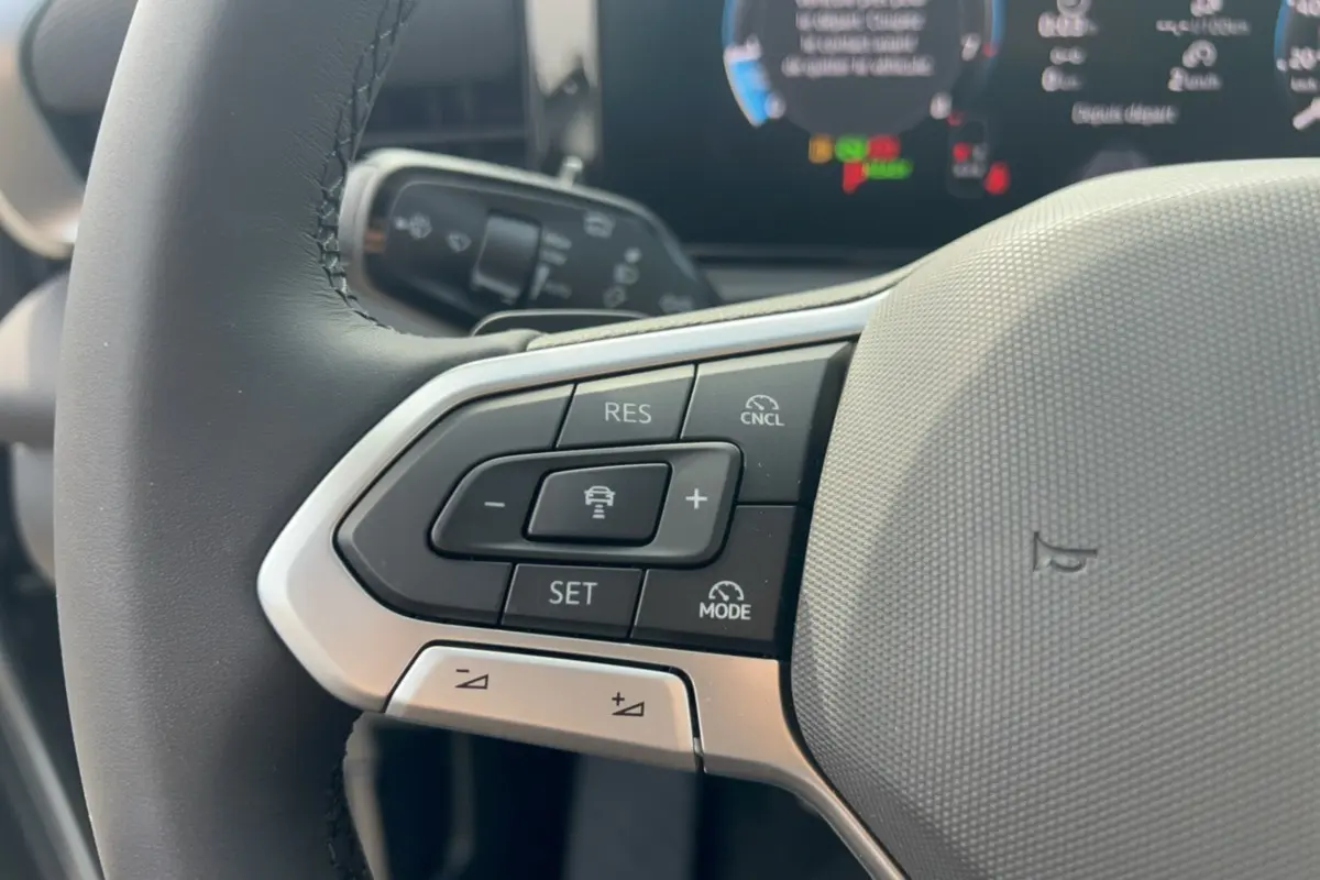 Gros plan sur le volant cuir multifonctions gris d’un Volkswagen T-Roc 2026, avec commandes de régulateur de vitesse.