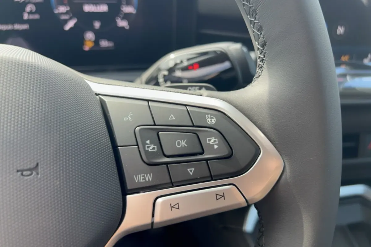 Gros plan sur les commandes multifonctions à gauche du volant cuir du Volkswagen T-Roc gris loup 2026.
