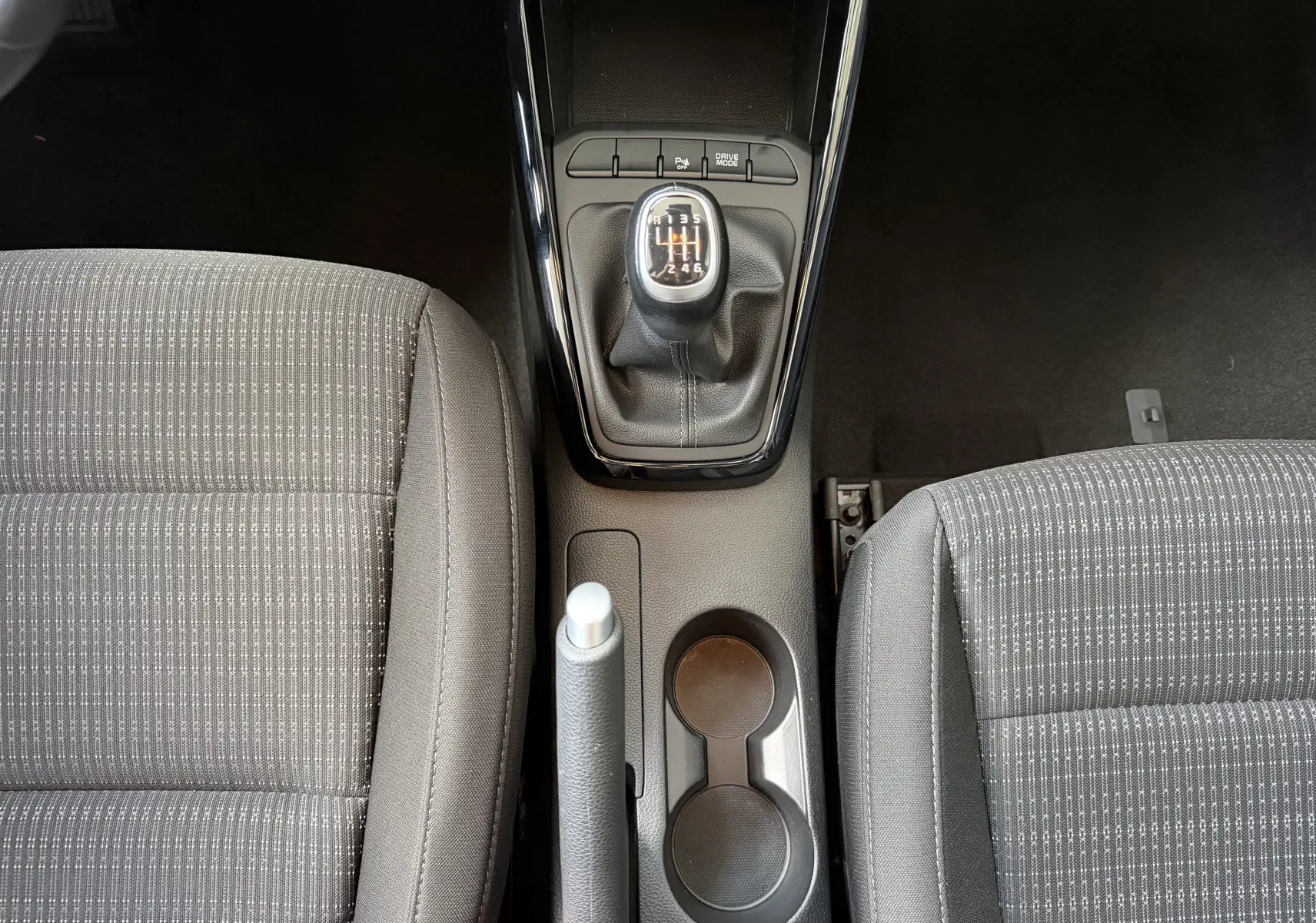 Vue plongeante sur la console centrale du Kia Stonic 2022, montrant la boîte manuelle et les sièges gris à motifs.