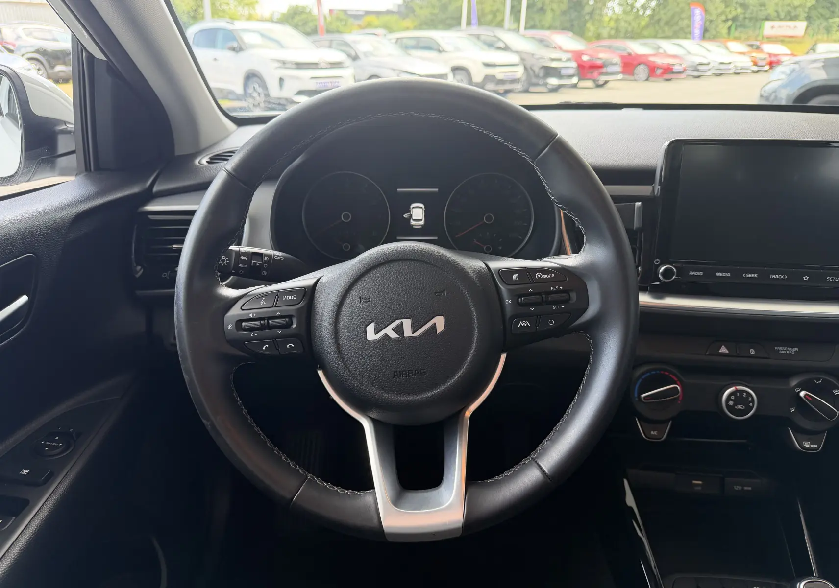 Vue intérieure centrée sur le volant noir de la KIA Stonic 2022, avec tableau de bord et écran tactile visibles.